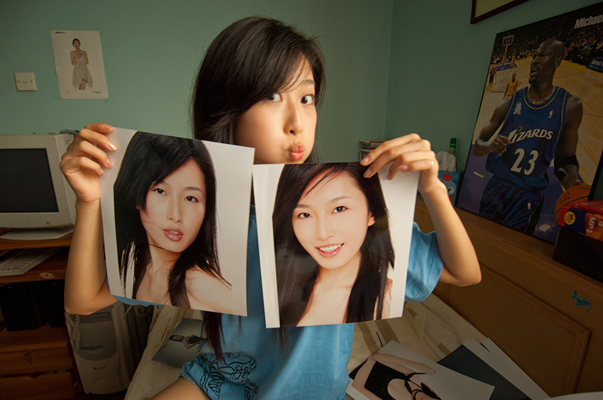 BEIJING, CHINA-SEPTEMBER, 2005: Young fashion model Wang Yili, picks new porfolio images and clowns with pictures of herself in her bedroom. She is emblematic of much of China's youth in urban settings as she rides a wave of change towards new opportunities and personal freedom and expression