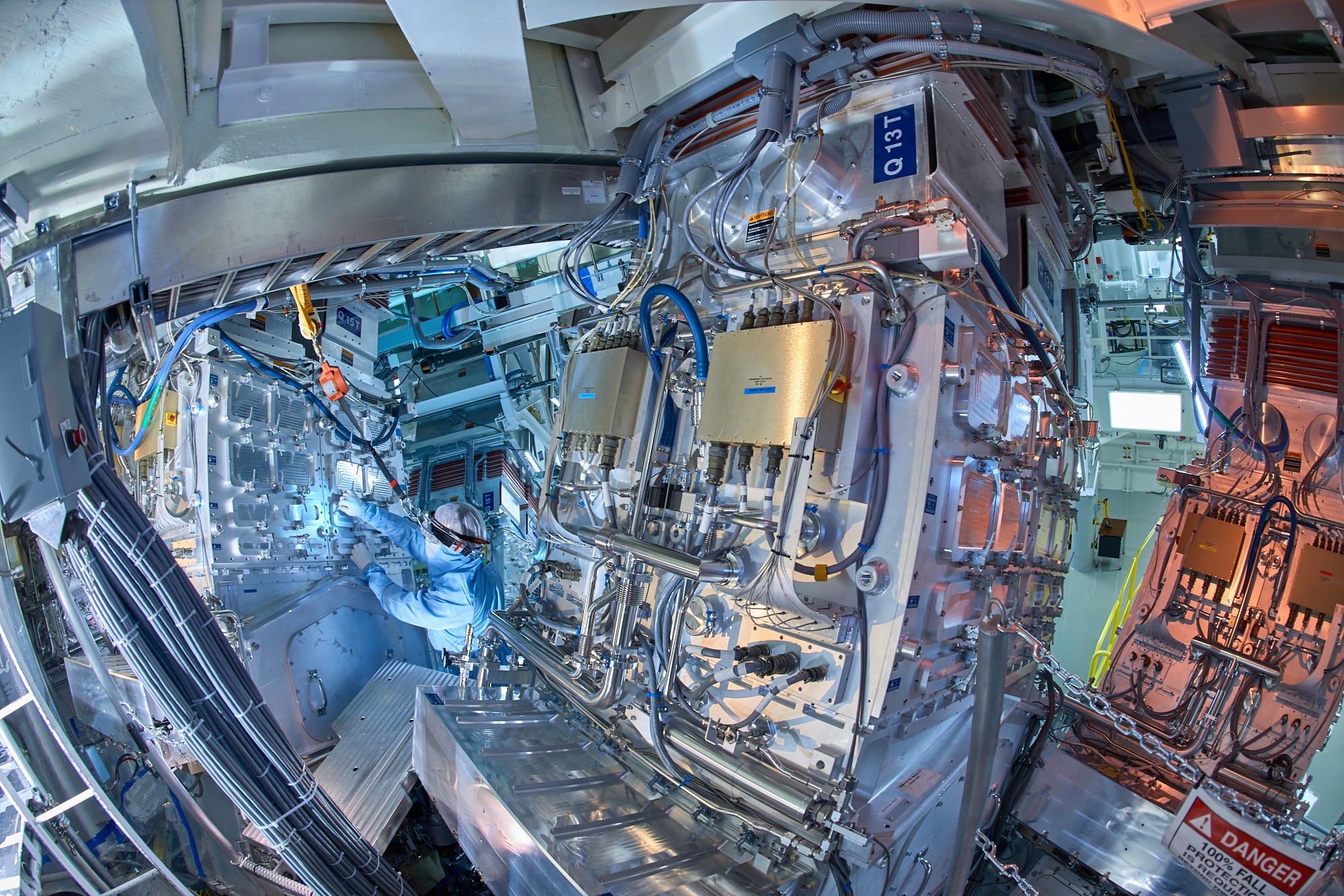 Photograph taken on top of the "Target Chamber" at NIF. A giant sphere in which the desired nuclear fusion reaction will occur.  192 lasers are directed from the laser bays into the center of sphere at a target that is the size of a BB.
Technician, Robert Cook, is pictured.